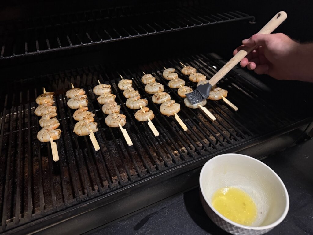 skewered shrimp being basted on the grill/smoker