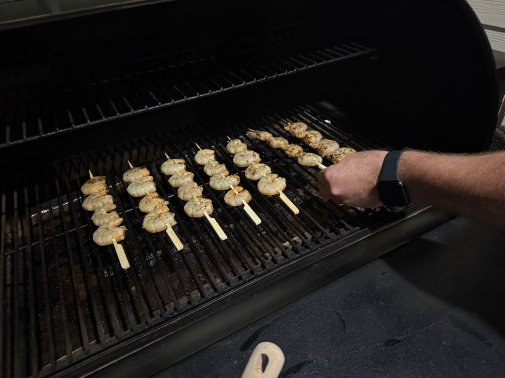 flipping skewered shrimp on the grill
