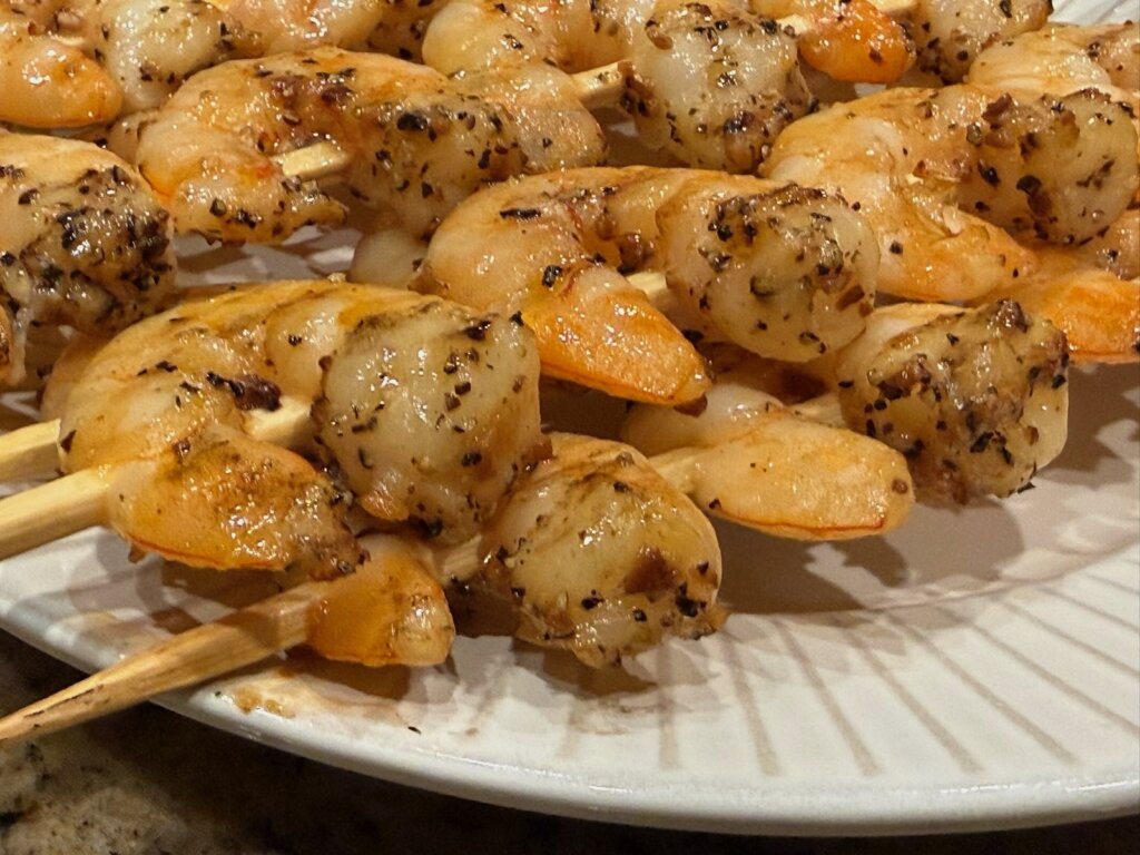 close-up of seasoned cooked skewered shrimp on plate, ready to eat