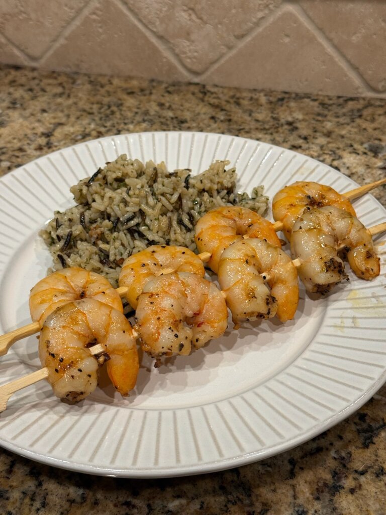 skewered shrimp on plate with rice pilaf
