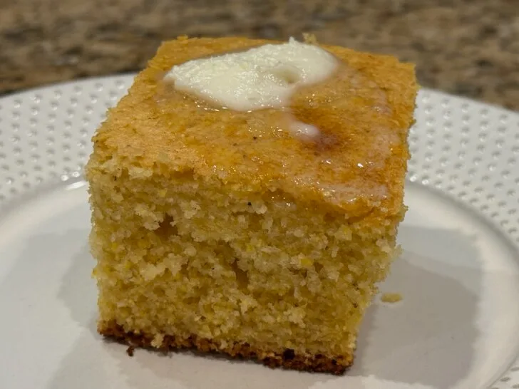 piece of cornbread on plate with butter and melted honey