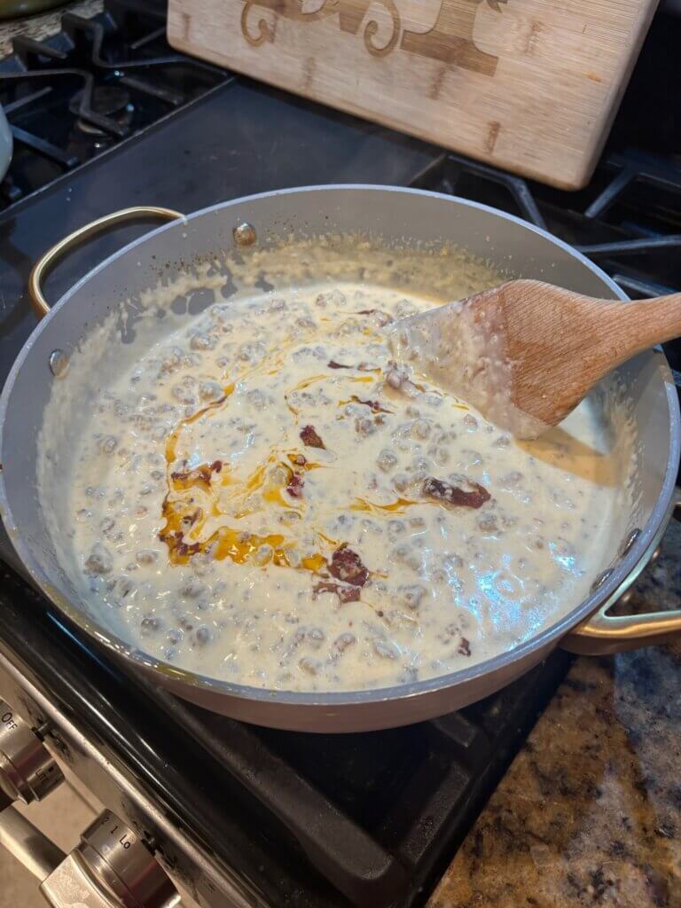 cheese sauce in pan with sun dried tomatoes