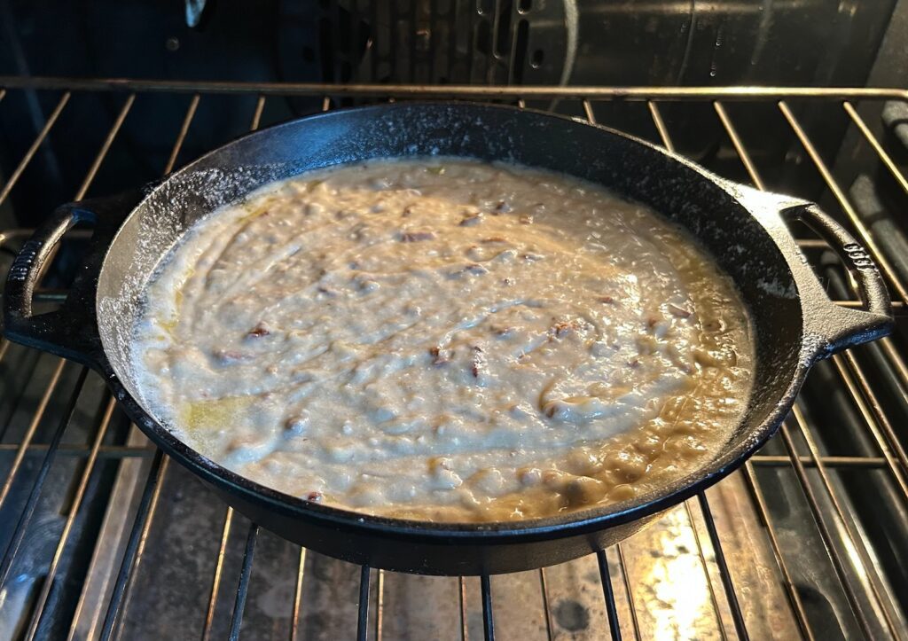 banana bread batter in cast iron skillet in oven