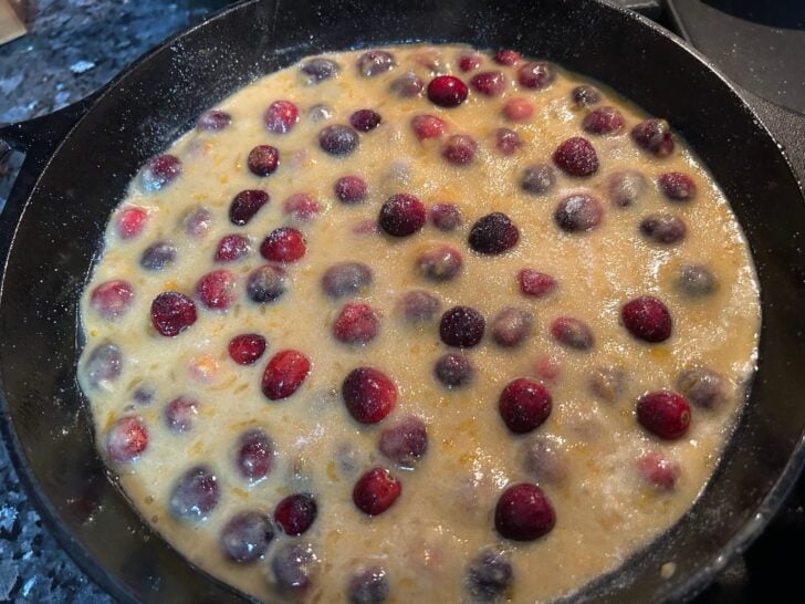 Orange Cranberry Skillet Cake batter in cast iron skillet with more cranberries on top