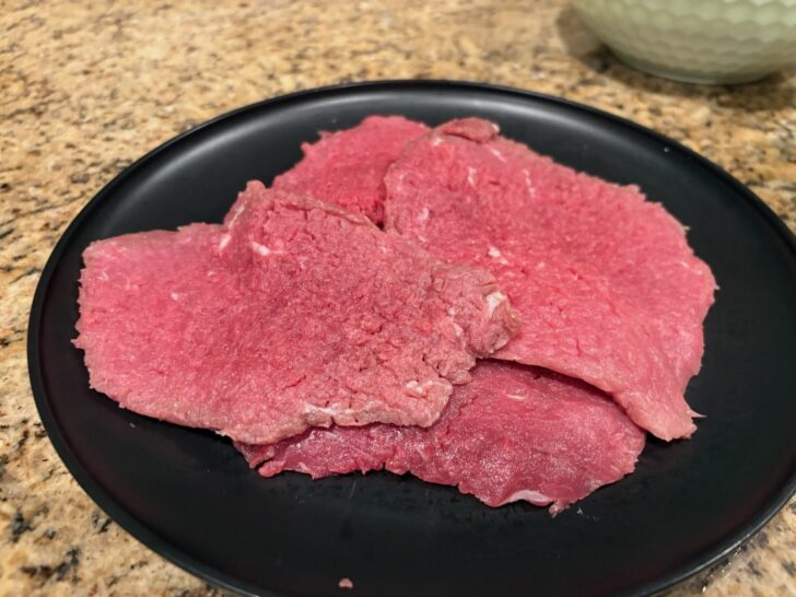 beef cutlets, raw, on plate