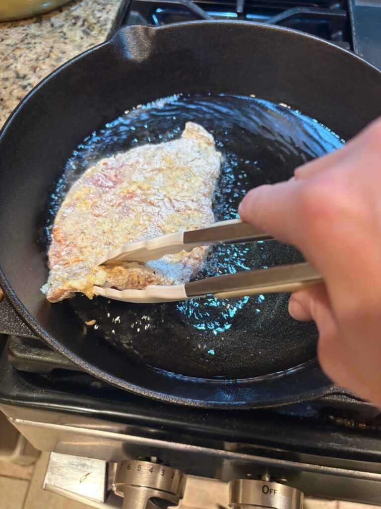 battered and floured steak in skillet