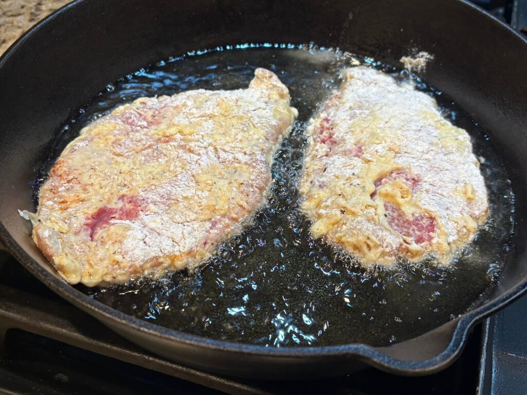 chicken fried steak simmering in skillet
