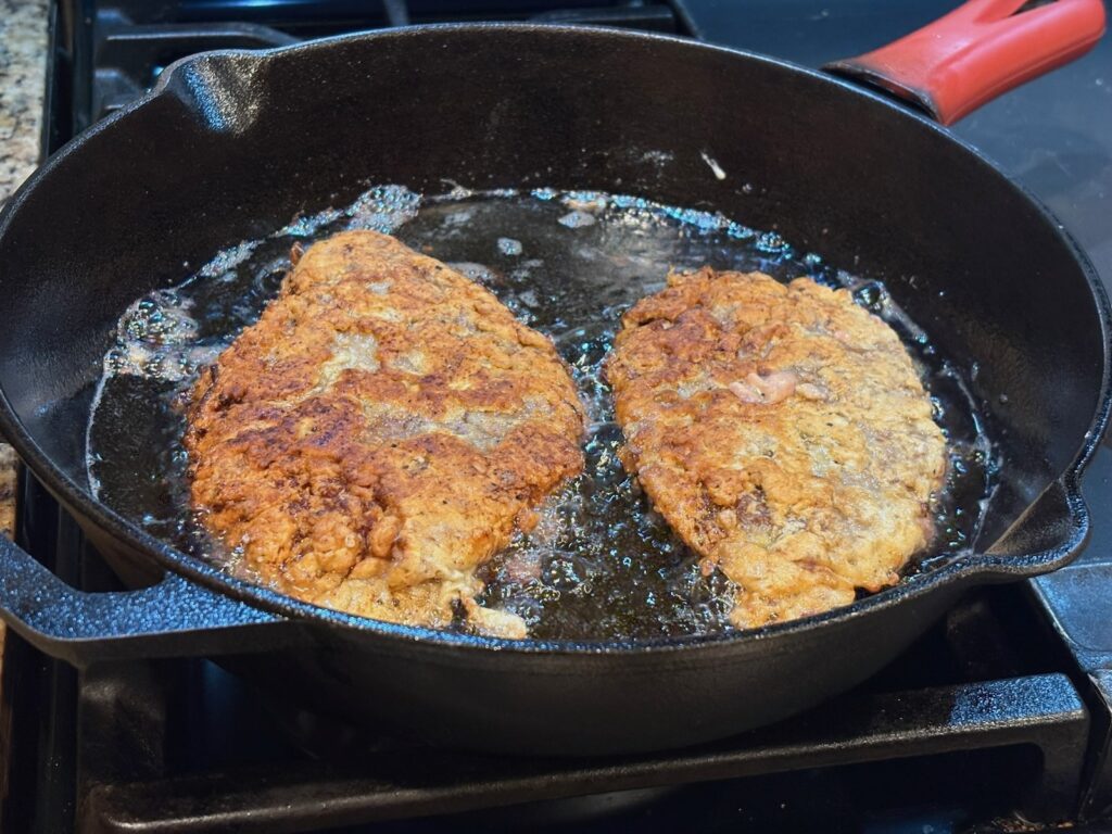 chicken fried steak in pan, nearly done