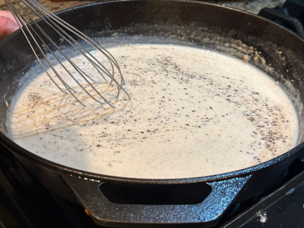 cream gravy with pepper (being whisked)