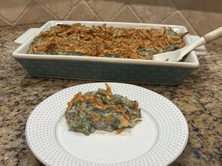 serving of green bean casserole with casserole dish behind