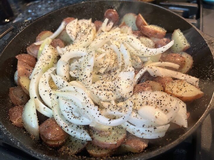 potatoes and onions in skillet with seasonings added