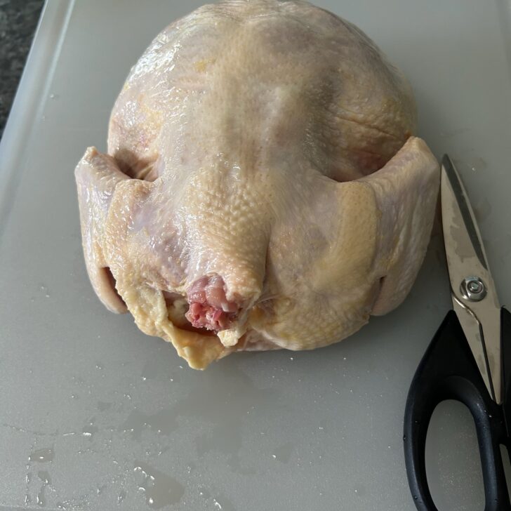 whole chicken, raw, with shears nearby