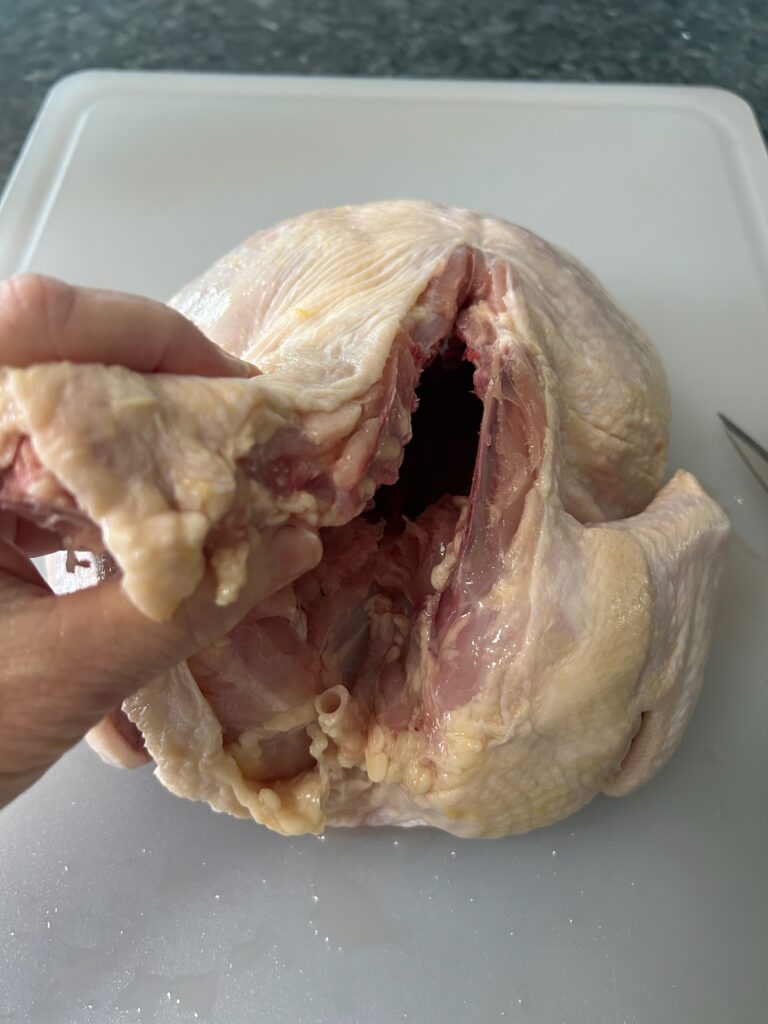 starting the process of removing the backbone from a whole chicken