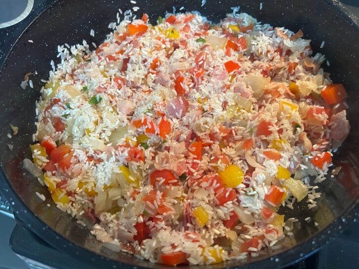 uncooked rice added to vegetables in skillet
