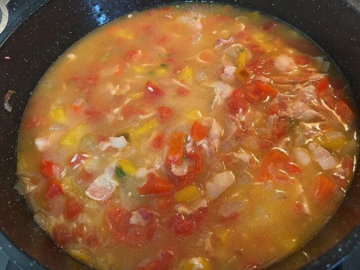 chicken broth added to rice and vegetables in skillet