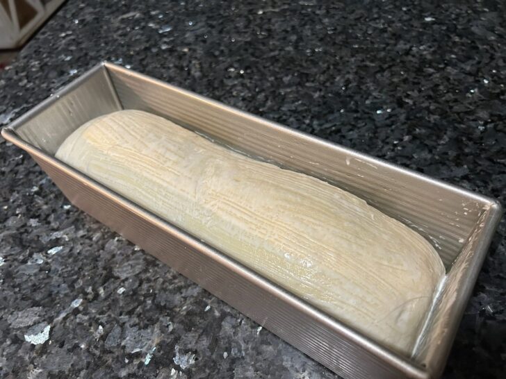 bread dough in pan, heavy cream applied to the top