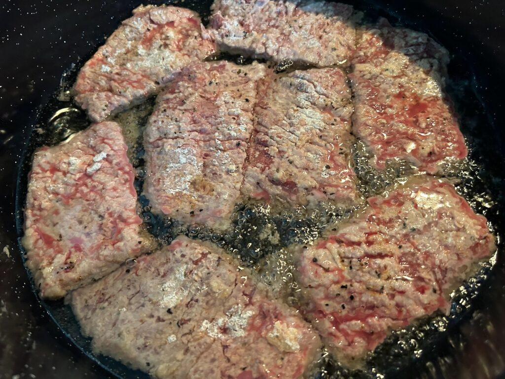 breaded beef frying in skillet