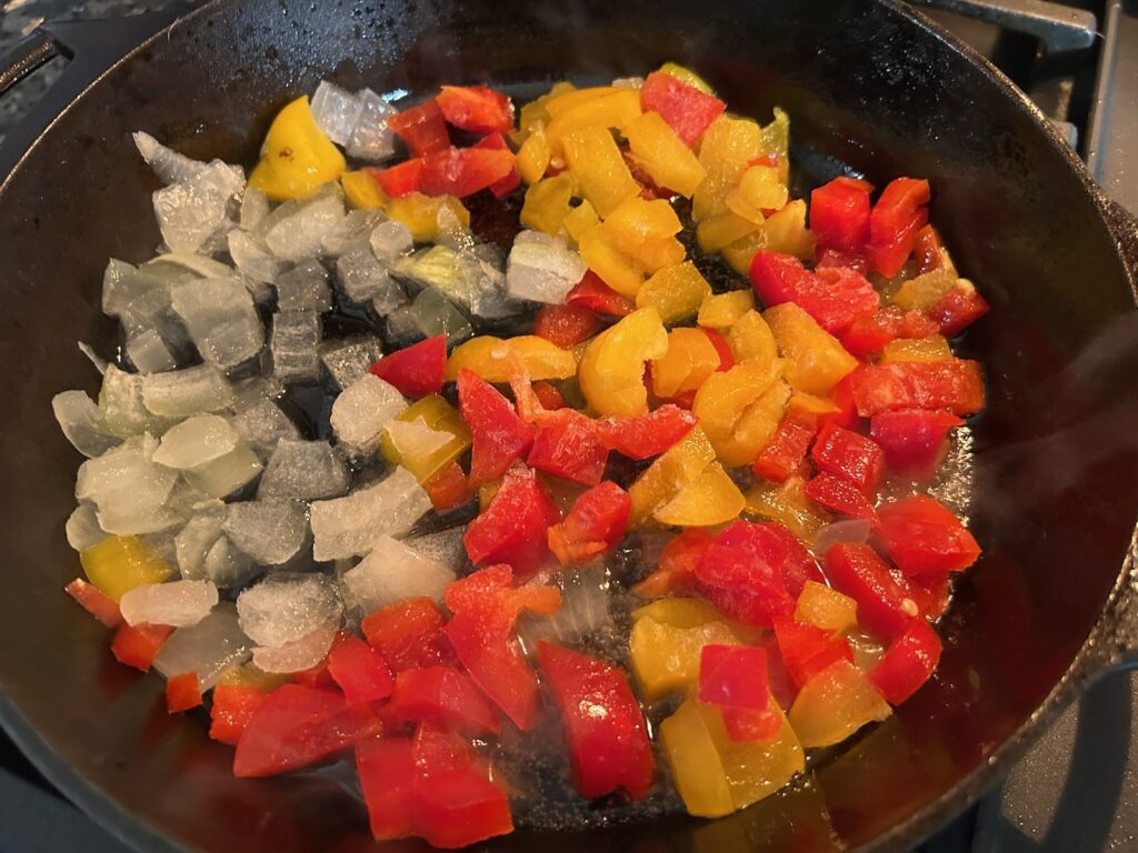 red and yellow peppers simmering in cast iron skillet with onions and jalapenos