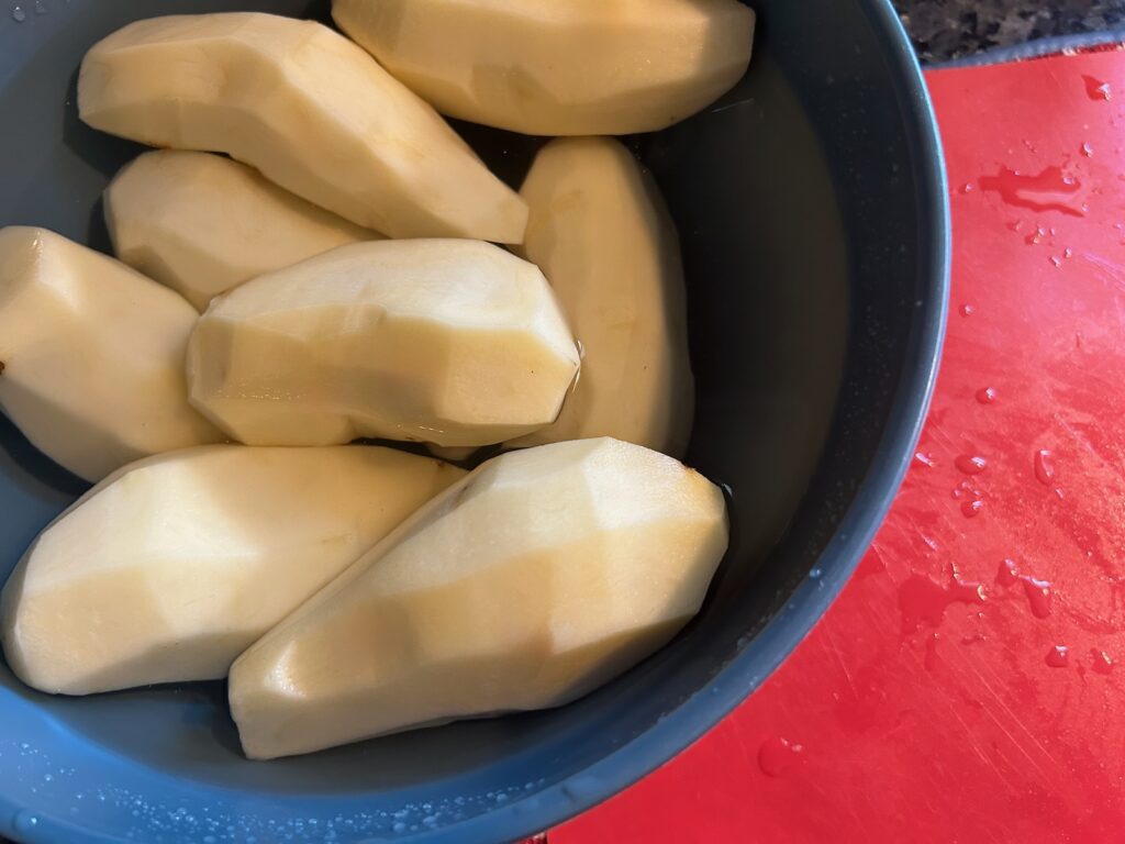 peeled potatoes in bowl of water
