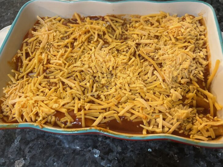 enchiladas covered in cheese ready to go in oven