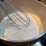 Easy Homemade Alfredo Sauce on stove, being whisked