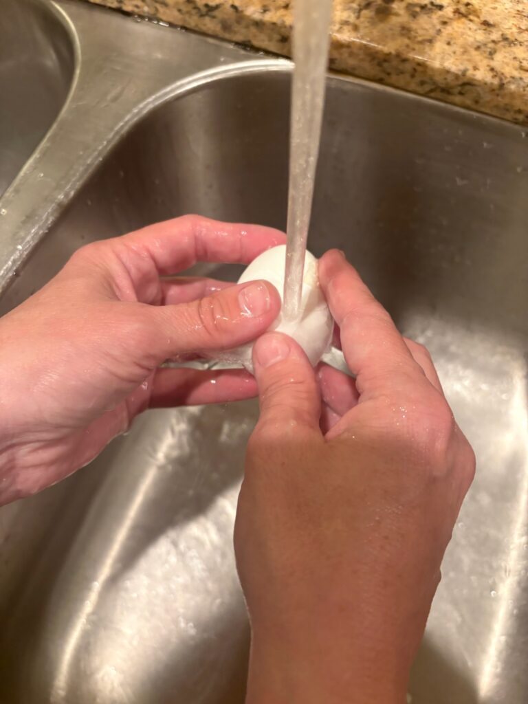 peeling an egg under running water