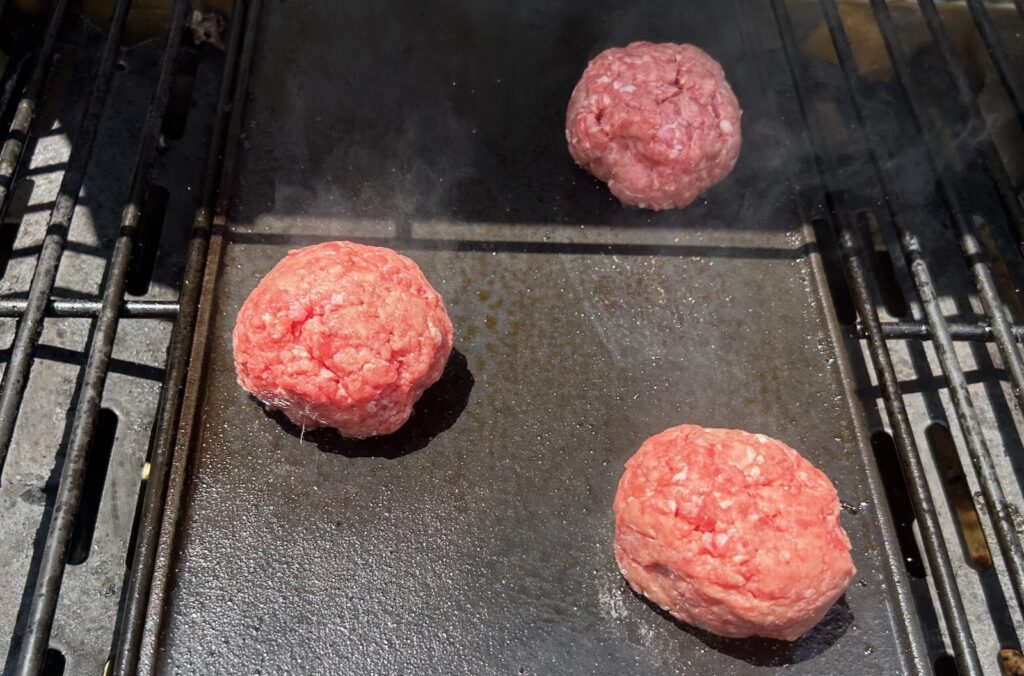 ground beef on grill before pressing down