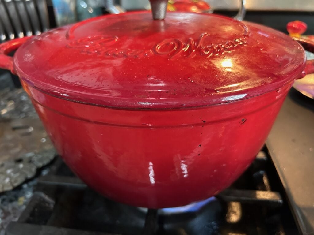Dutch Oven Beef Stew (Texas Style) simmering on stove in red dutch oven