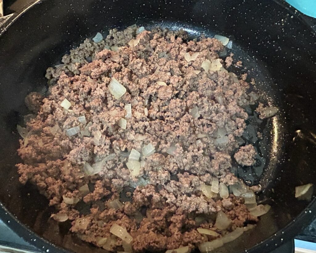 cooked ground beef with onion in skillet