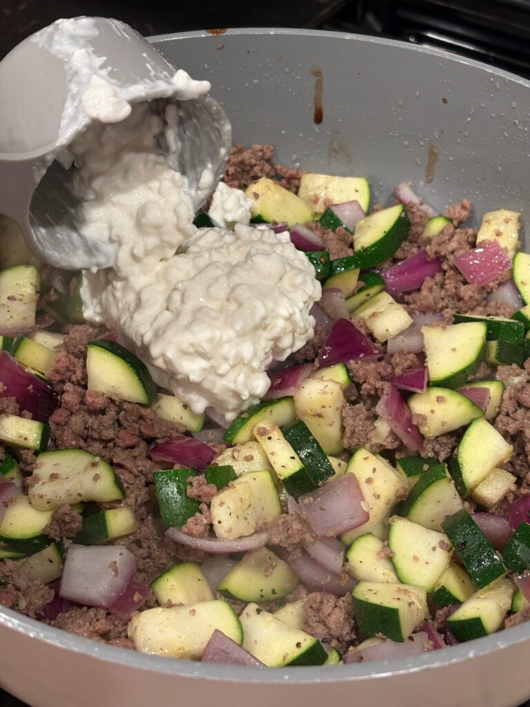 adding cottage cheese to Creamy High Protein Beef and Zucchini Pasta
