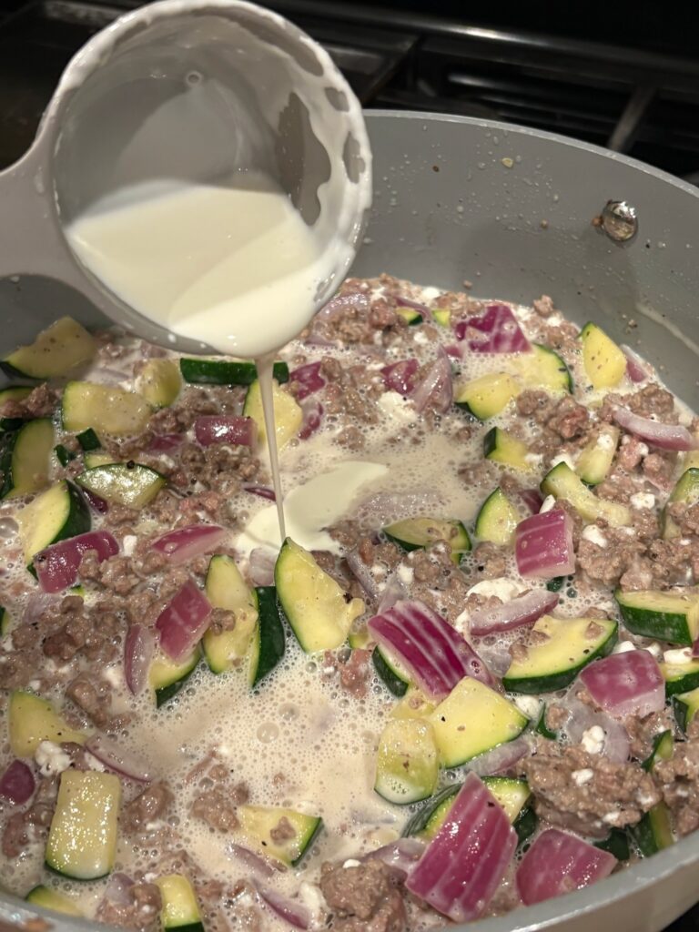 adding cream to Creamy High Protein Beef and Zucchini Pasta