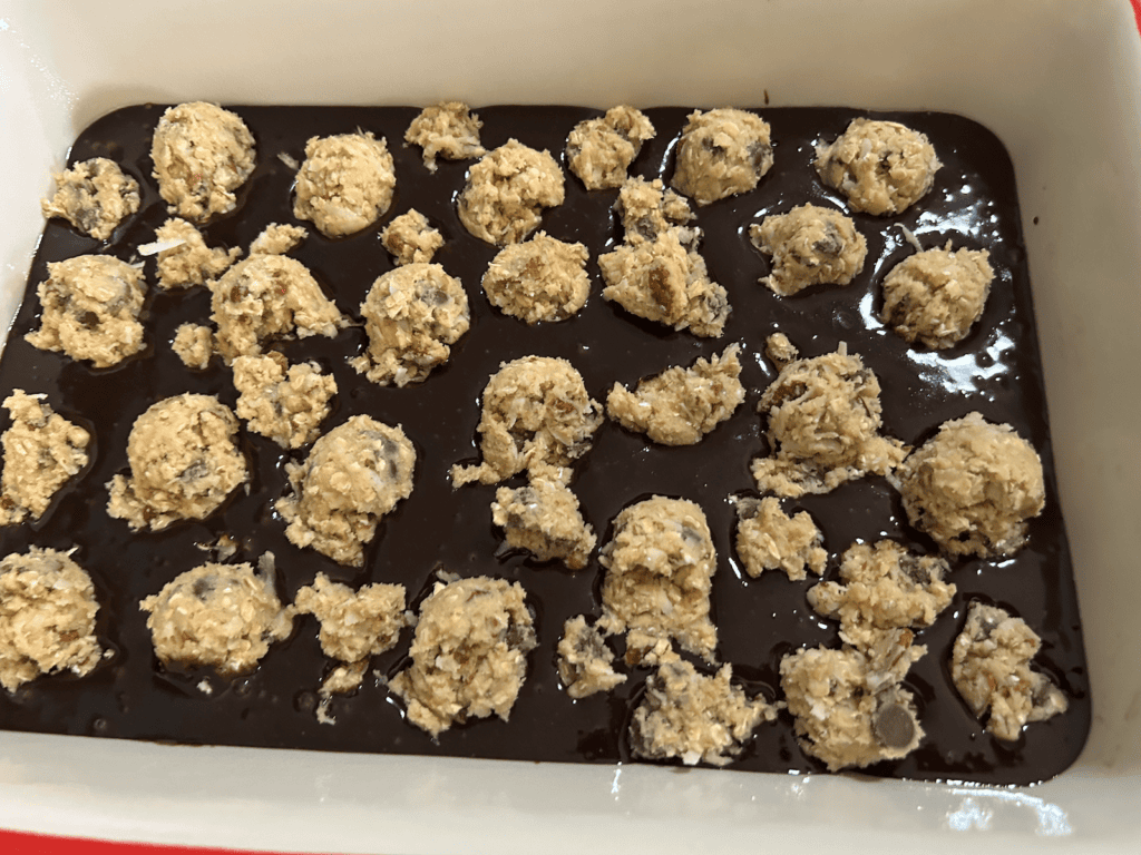 brownie batter in dish with scoops of cowboy cookie dough on top