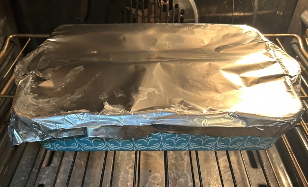 Old-Fashioned Creamy Scalloped Potatoes covered with foil in oven