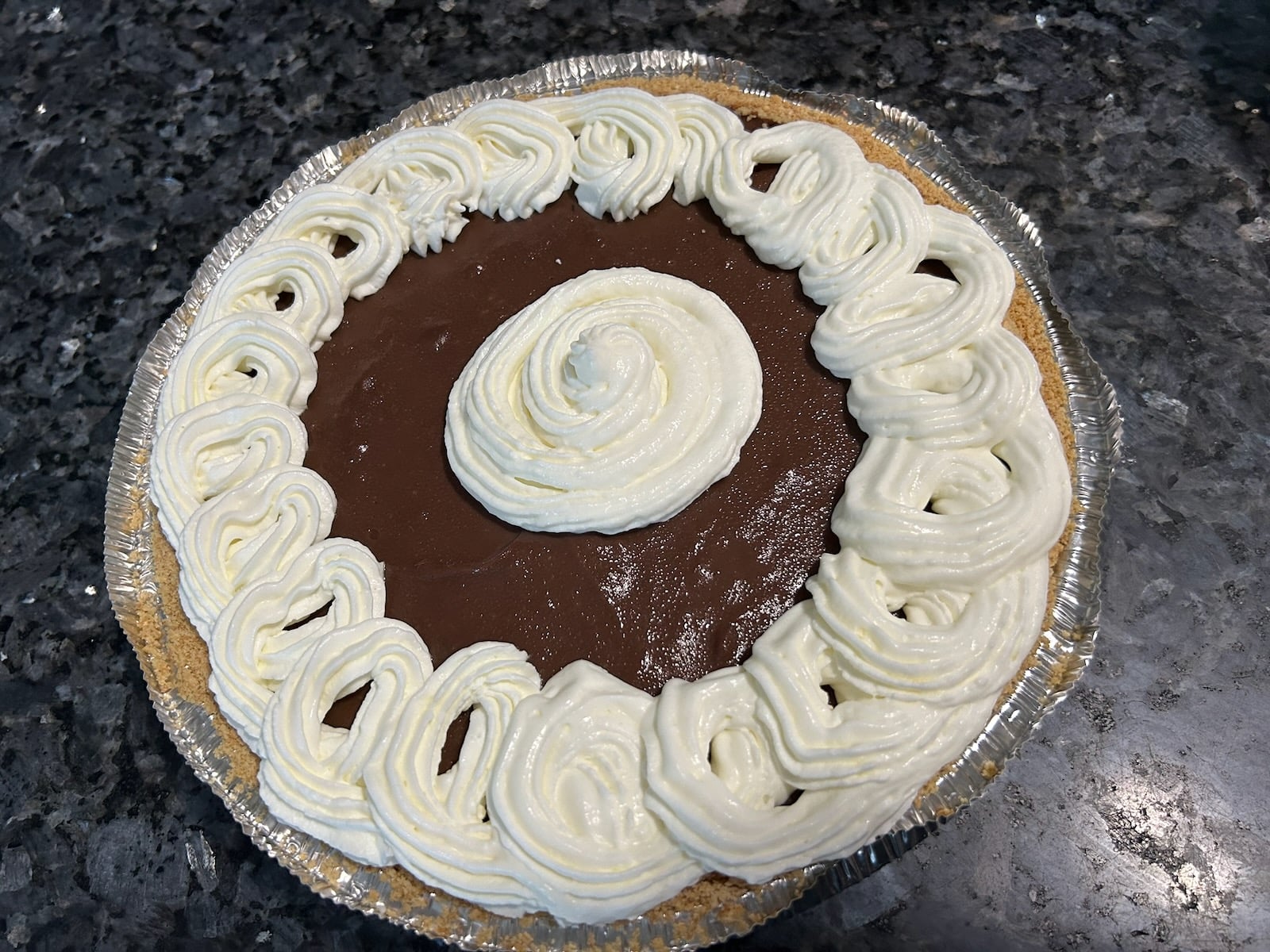 adding whipped cream to chocolate pie